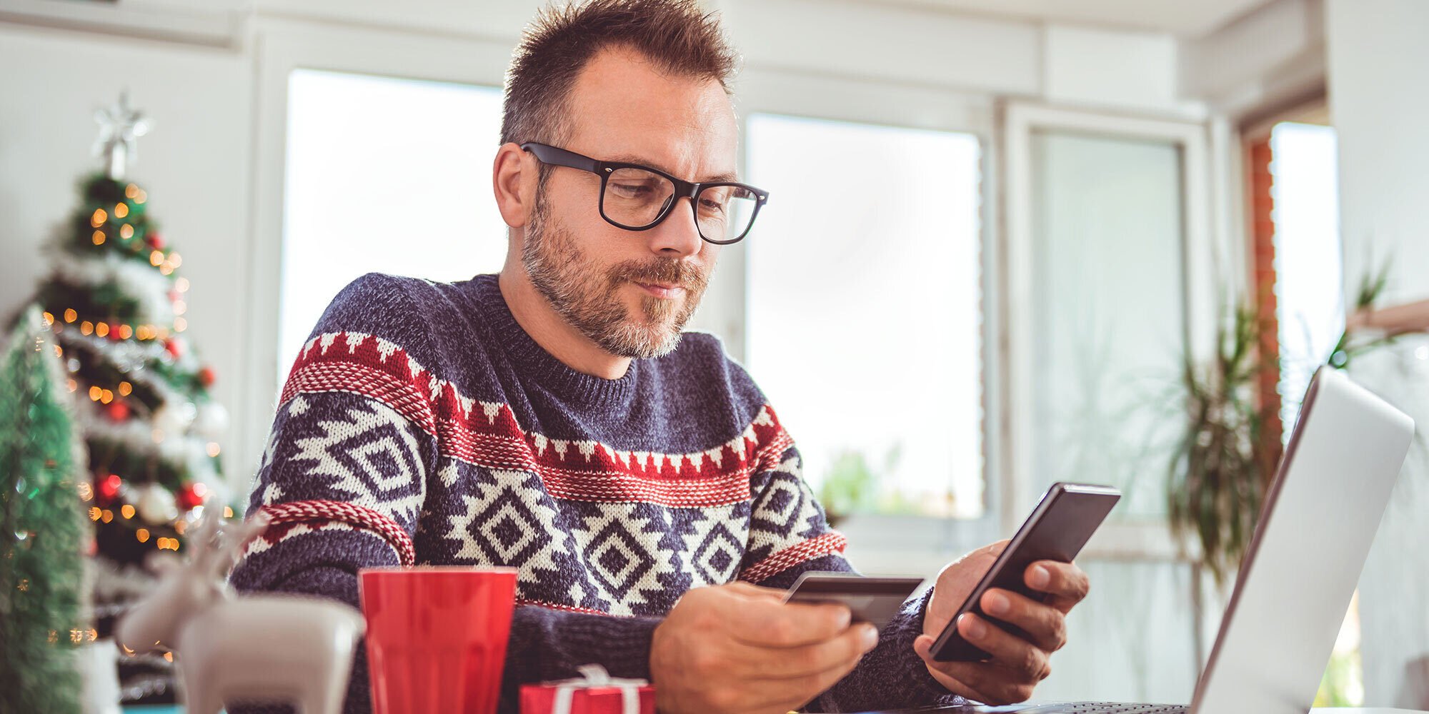 Man looking at his phone holding a credit card