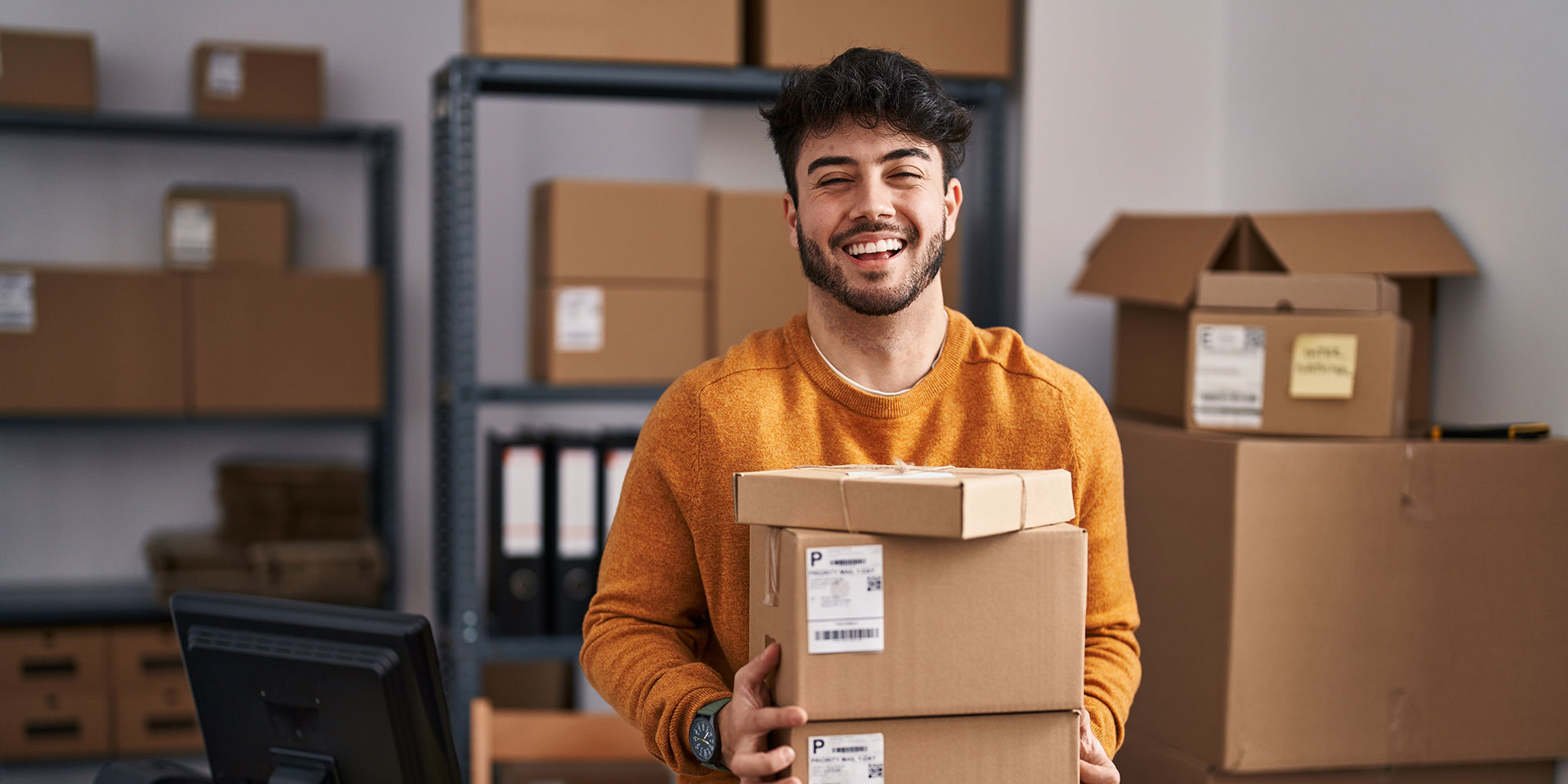 Young man smiling and holding some packages.