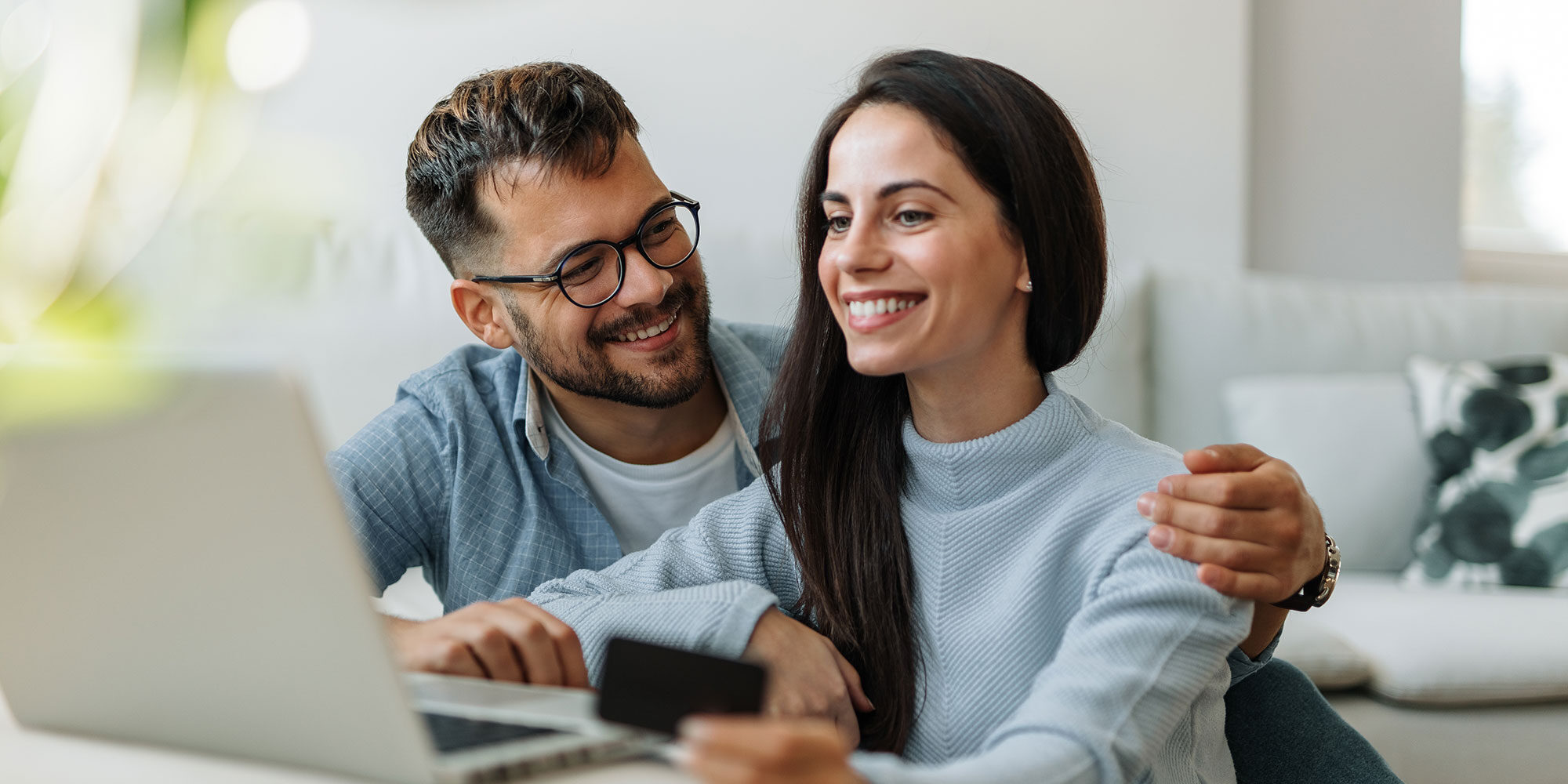 Couple smiling and holding credit card.