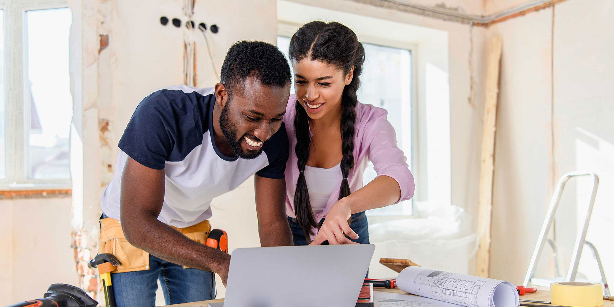 A couple pointing at their open laptop. 