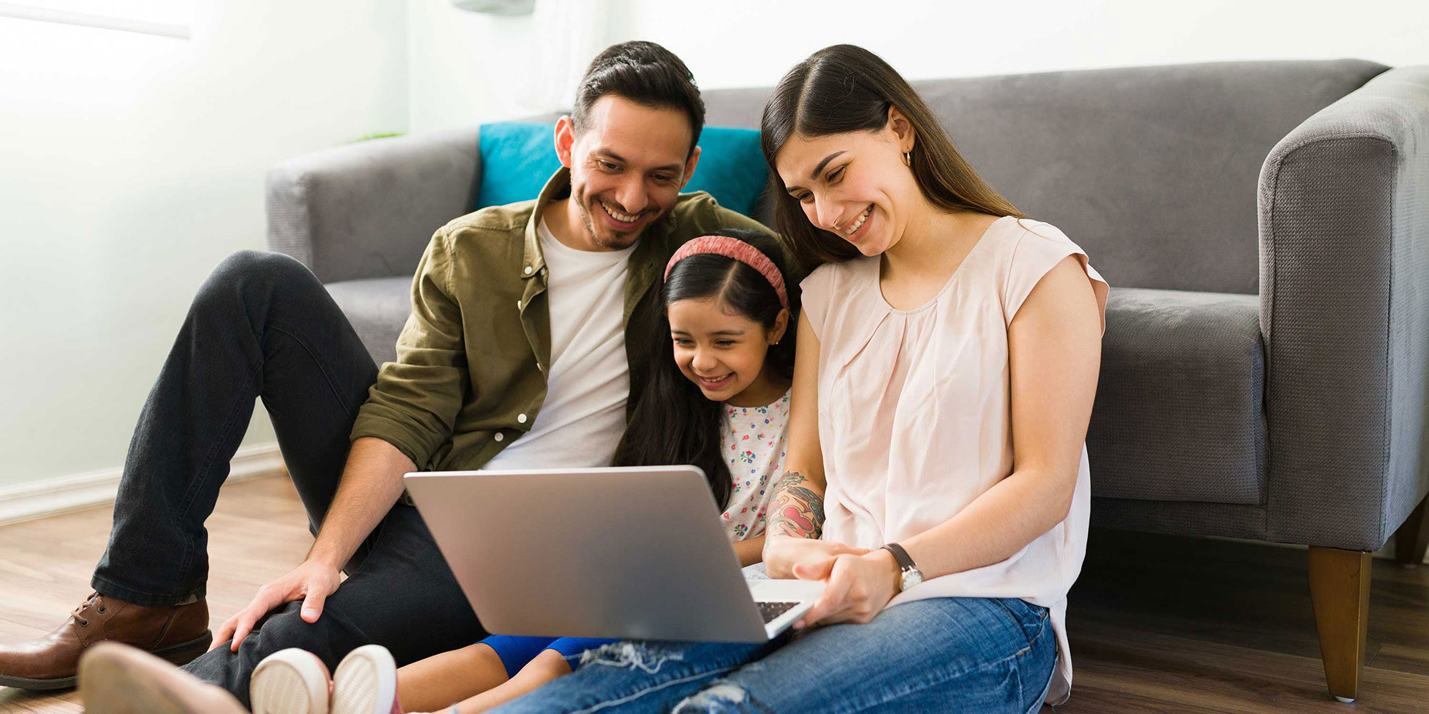 Happy family sitting together, looking at their laptop.