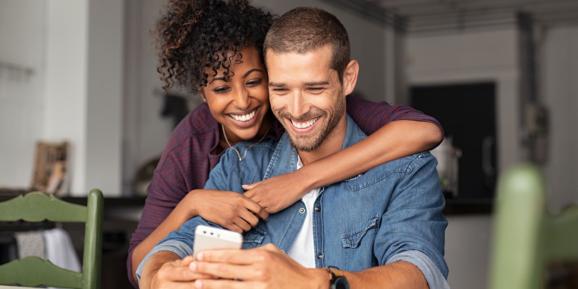 Smiling couple looking at a smartphone together.