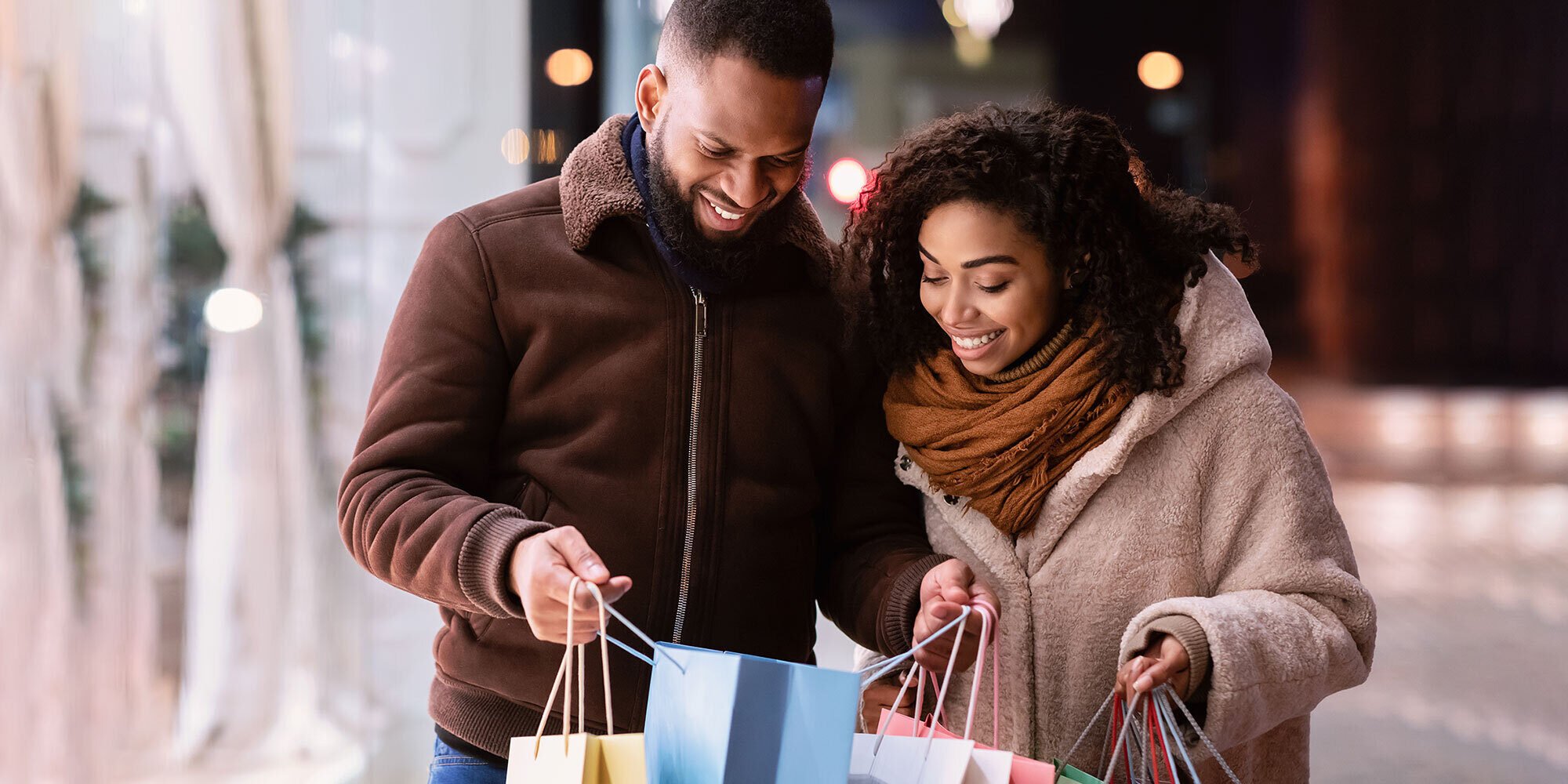 Couple holiday shopping, looking inside shopping bag. 