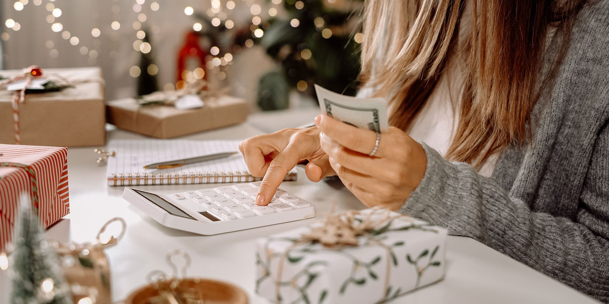 Woman hand holding cash, typing into a calculator. 