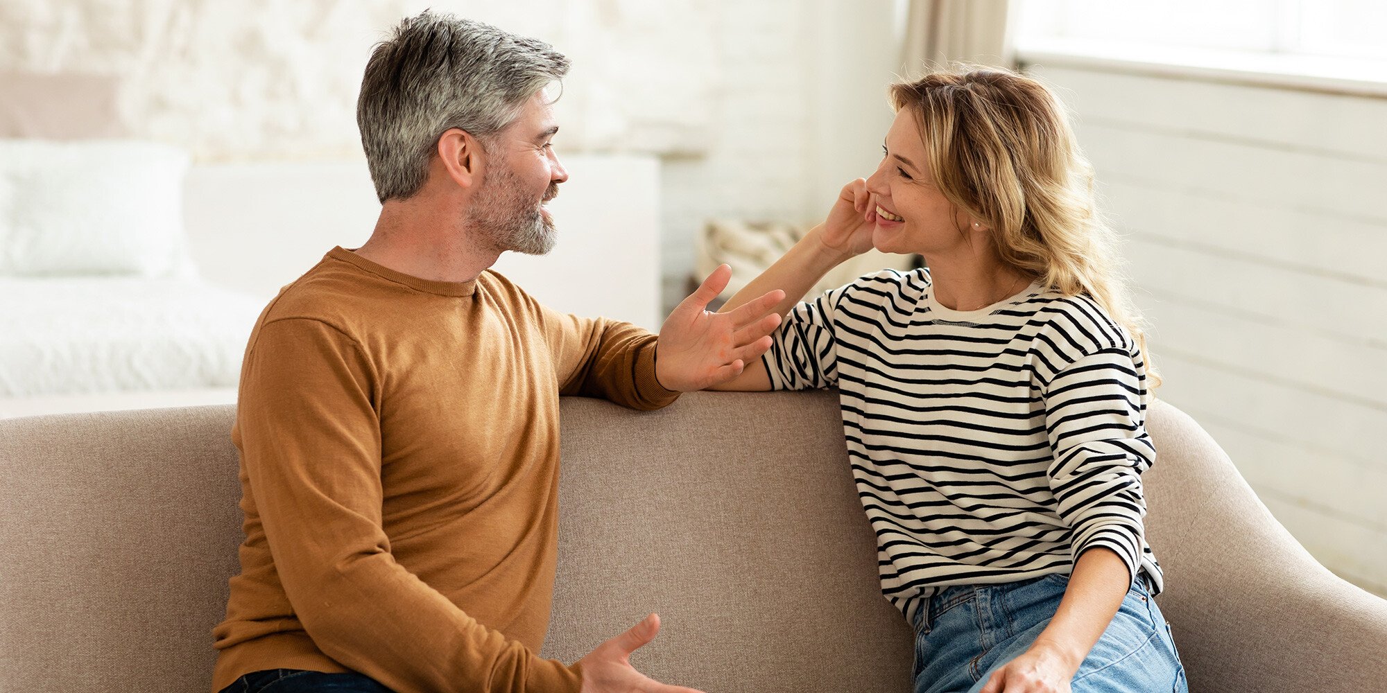 An older couple talking on the couch.