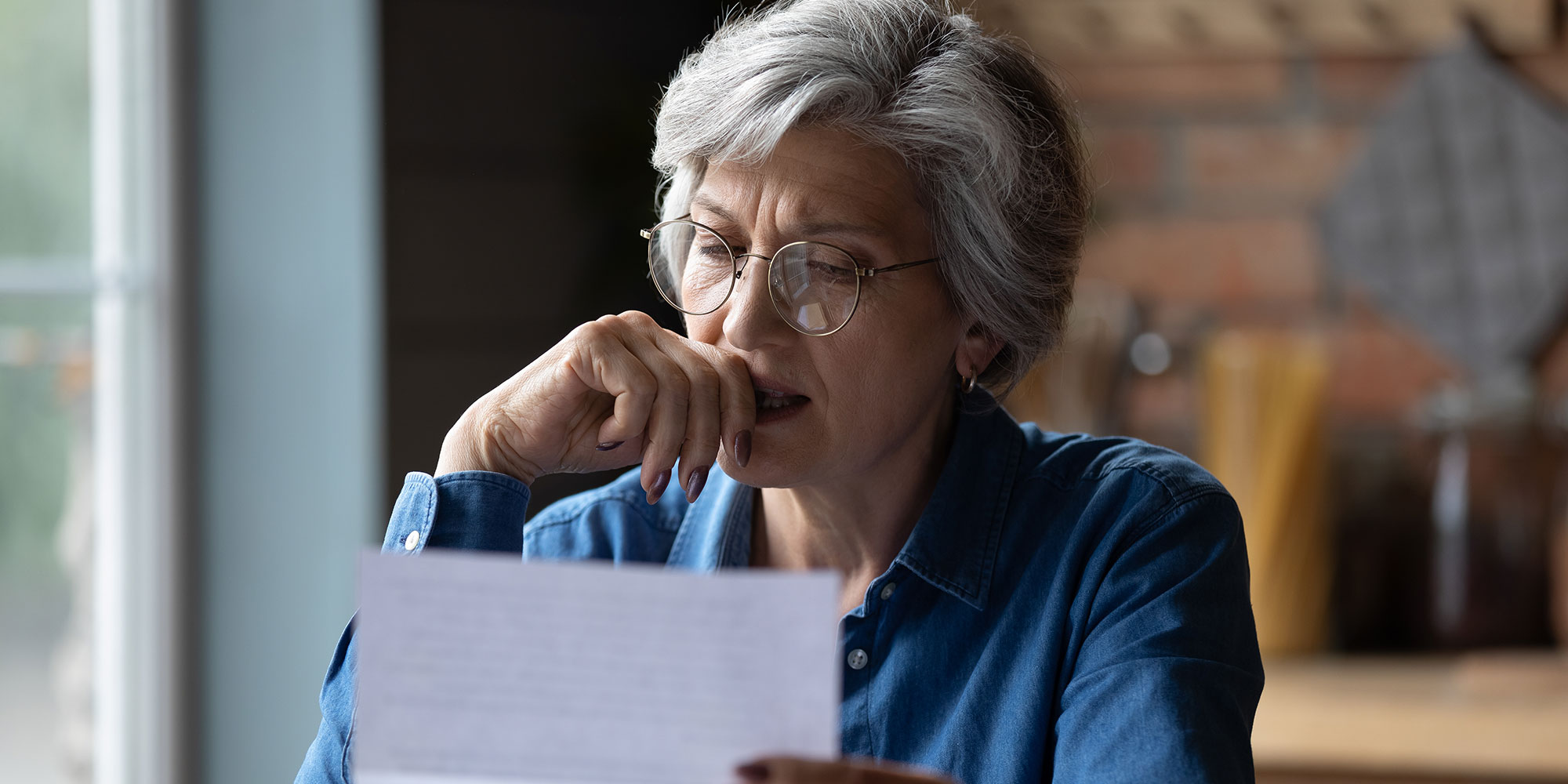 Old woman looking looking at a paper and thinking. 