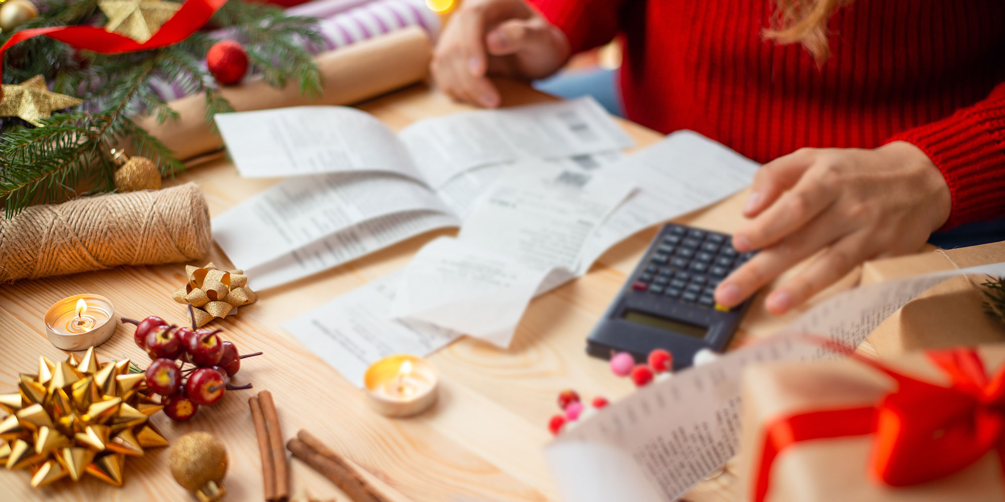 Hand typing on calculator, papers on desk. 