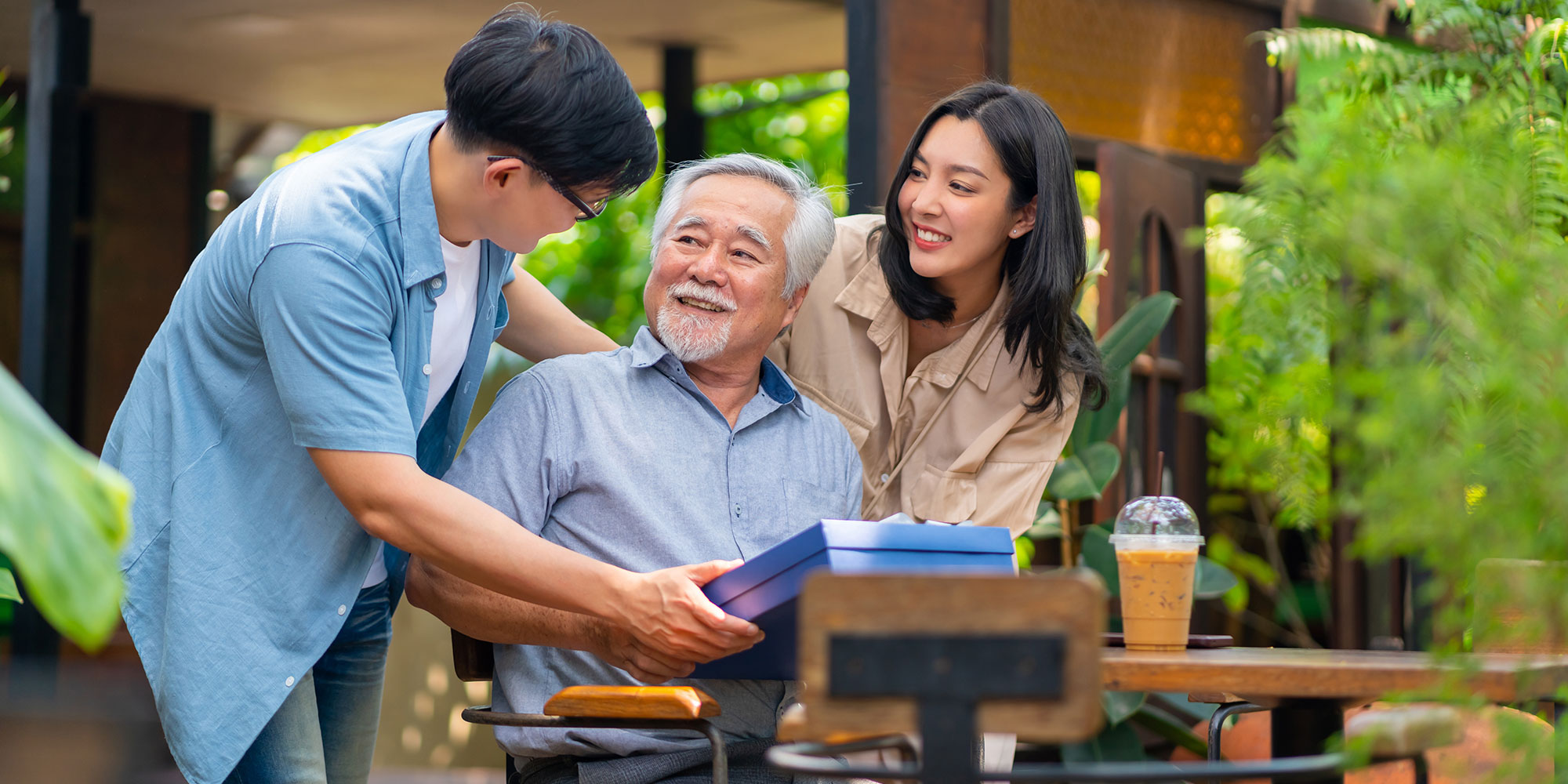 Two young adults giving an older man a gift.